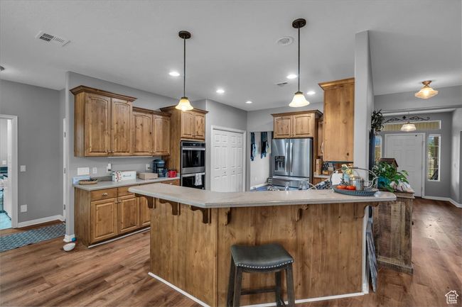 Kitchen with visible vents, baseboards, a peninsula, appliances with stainless steel finishes, and dark wood-style floors | Image 16
