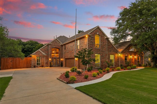 Twilight view of traditional home featuring concrete driveway, extended parking, an 3 car oversized attached garage, a gate with additional parking and RV parking behind the gate and brick siding | Image 35