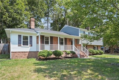 Split level home featuring covered porch and a front yard | Image 1