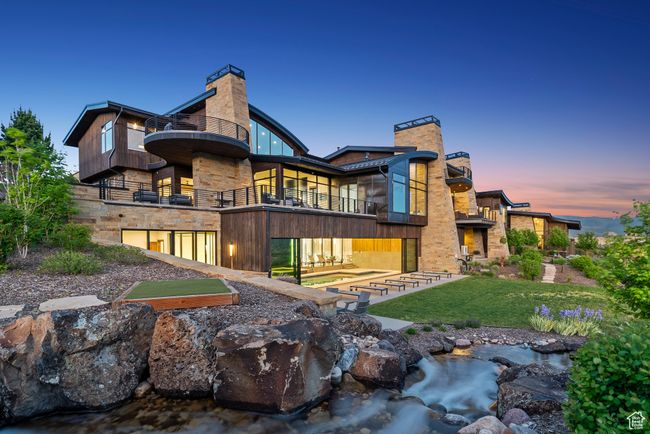 Rear view of house featuring a balcony, stone siding, a chimney, and a lawn | Image 67