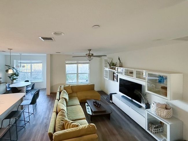 Living room with a healthy amount of sunlight, a ceiling fan, visible vents, and wood-look finished floors | Image 5