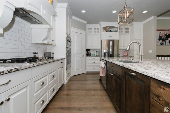 Kitchen with a sink, dark brown cabinetry, stainless steel appliances, custom range hood, and white cabinets | Image 33