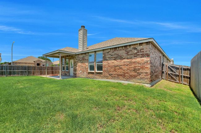Back of house featuring brick siding, a fenced backyard, a chimney, and a patio | Image 29