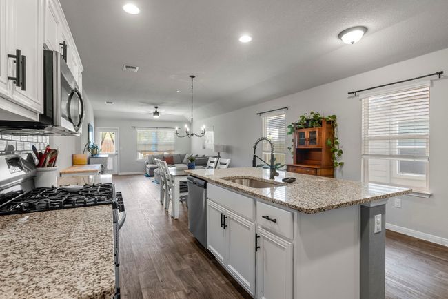 Kitchen with stainless steel appliances, open floor plan, dark wood-style flooring, white cabinetry, and recessed lighting | Image 12