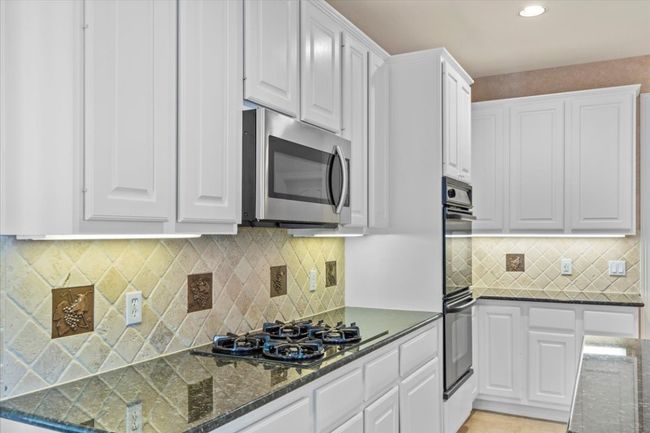This kitchen features a gas cooktop and ample cabinet space, making it both functional and stylish. | Image 11