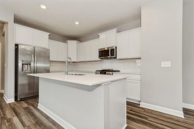 (Photo of similar home, finishes will vary) Welcome to the Marquette! This spacious kitchen includes a large center island, quartz countertops, recessed lighting, LVP wood floors, stainless appliances and more. | Image 1