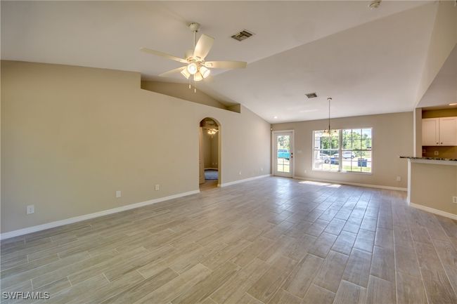 Unfurnished living room with lofted ceiling, a ceiling fan, visible vents, and light wood-style floors | Image 18