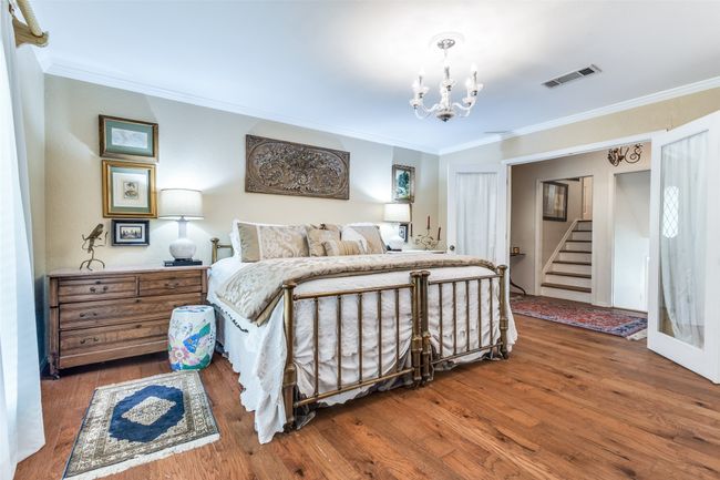 Bedroom with wood finished floors, crown molding, and a chandelier | Image 17