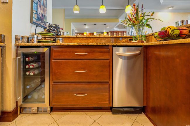 Kitchen featuring beverage cooler, stainless steel dishwasher, crown molding, light tile patterned floors, and light stone countertops | Image 17