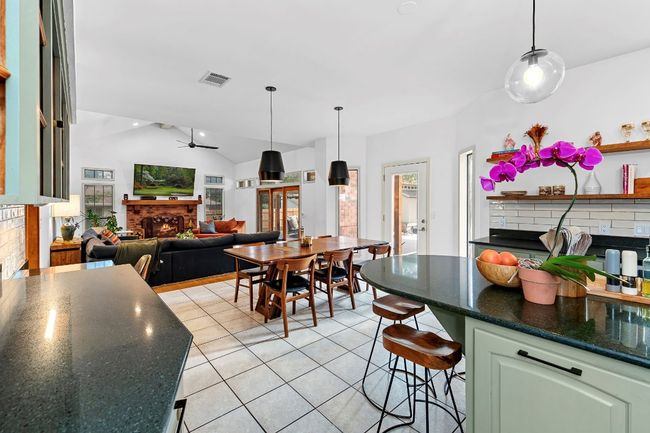 Kitchen featuring a fireplace, lofted ceiling, light tile patterned floors, a breakfast bar, and pendant lighting | Image 16