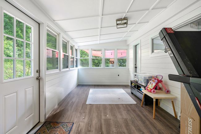 Sunroom with plenty of natural light, wood finished floors, lofted ceiling, and wooden walls | Image 24