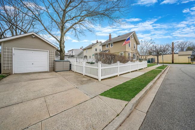 View of property exterior with driveway, an outdoor structure, fence, a residential view, and a garage | Image 26