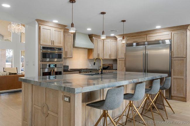 Main kitchen with luxury counters, luxury appliances, bar seating, and custom cabinets | Image 18