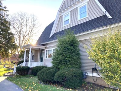 Side entry to kitchen with small porch with columns, rails and low maintenance vinyl floor boards. Entry is adjacent to driveway and detached garage | Image 2