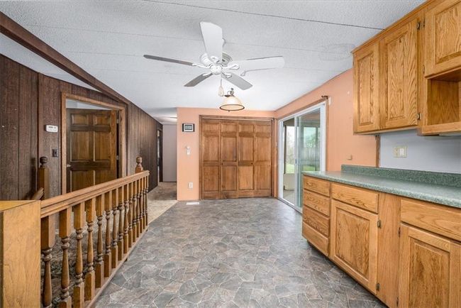 Kitchen with wood walls, a ceiling fan, stone finish floor, and a textured ceiling | Image 18