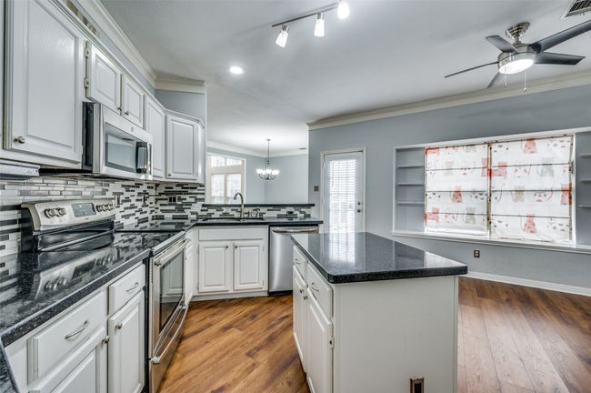 Kitchen featuring appliances with stainless steel finishes, ornamental molding, a chandelier, a ceiling fan, and backsplash | Image 7