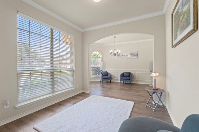 Living area with wood finished floors, arched walkways, ornamental molding, a chandelier, and baseboards | Image 4