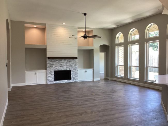Unfurnished living room with arched walkways, dark wood-style flooring, ceiling fan, built in features, and recessed lighting | Image 14