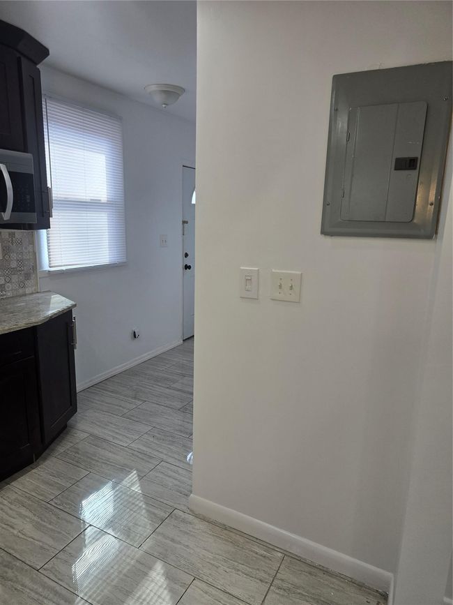 Kitchen featuring dark cabinets, electric panel, and baseboards | Image 8