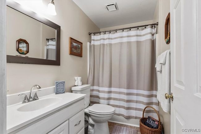 Bathroom featuring toilet, vanity, and curtained shower | Image 26