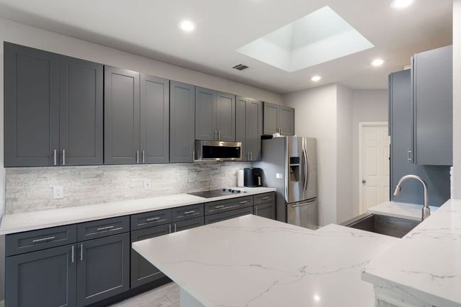 Kitchen featuring light stone counters, a sink, recessed lighting, and appliances with stainless steel finishes | Image 17