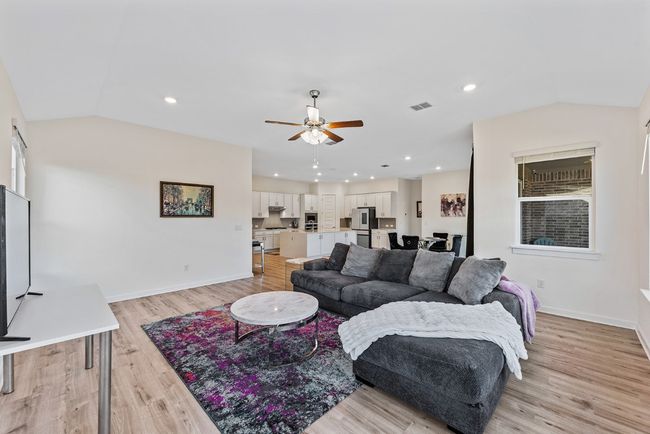 Living room with visible vents, baseboards, vaulted ceiling, light wood-style flooring, and a ceiling fan | Image 14