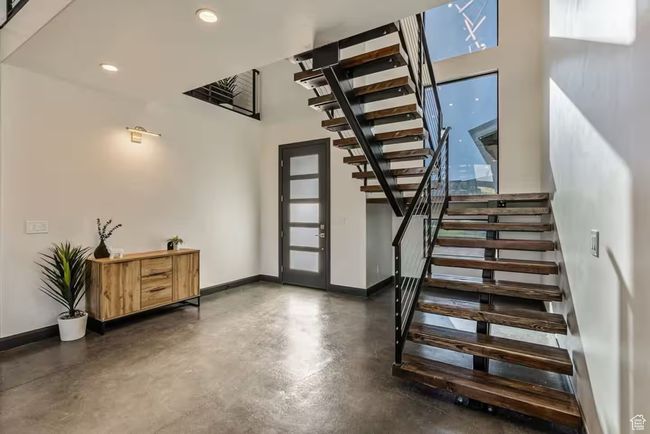 Foyer entrance featuring concrete flooring, recessed lighting, a high ceiling, baseboards, and stairs | Image 34