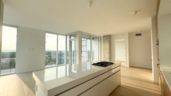 Kitchen featuring stainless steel gas cooktop, light wood-type flooring, baseboards, a wall of windows, and a center island | Image 14