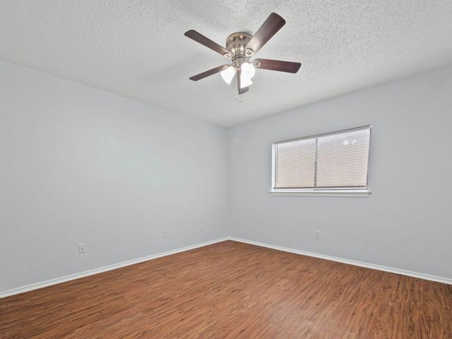 Empty room with wood finished floors, a ceiling fan, and a textured ceiling | Image 10