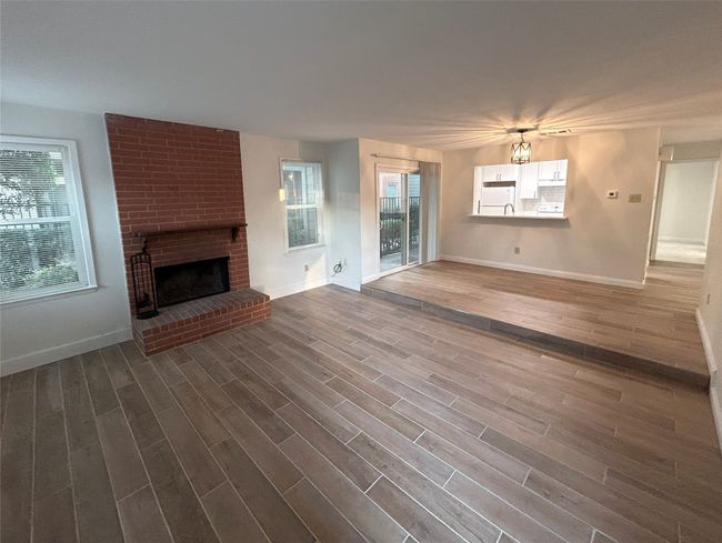 Unfurnished living room featuring wood-type flooring and a brick fireplace | Image 5