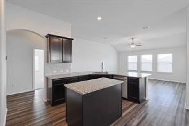 Kitchen with light countertops, dark wood-type flooring, a ceiling fan, a peninsula, and a kitchen island | Image 5