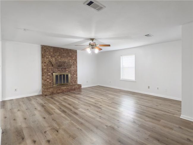Unfurnished living room featuring ceiling fan, wood finished floors, and a fireplace | Image 4