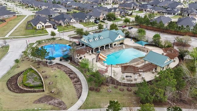 Aerial view of the Retreat in The Falls at Imperial Oaks—featuring a resort-style pool with waterslides, splash pad, shaded pavilions, and clubhouse. A perfect community hub for fun, relaxation, and gatherings. | Image 44