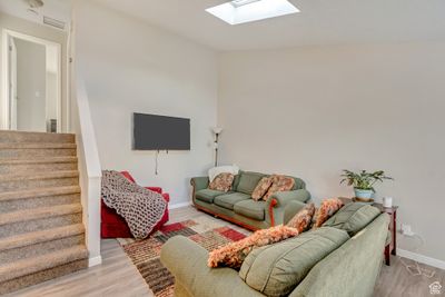 Living room featuring light wood-type flooring and lofted ceiling with skylight | Image 3