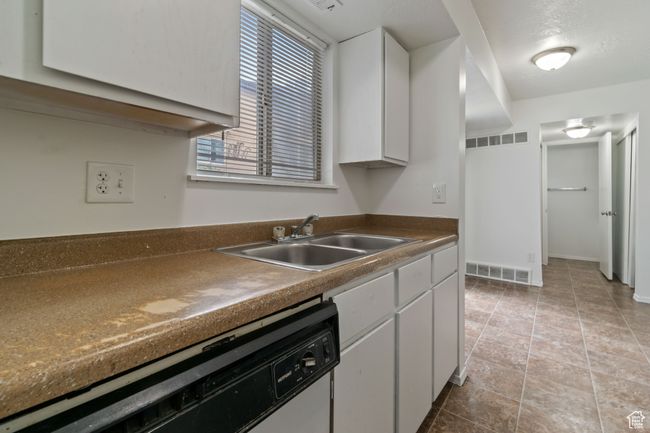 Kitchen featuring white dishwasher, white cabinets, and dark countertops | Image 7
