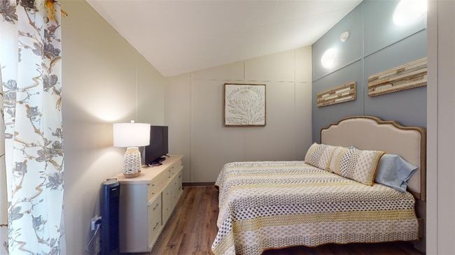 Bedroom with lofted ceiling and wood finished floors | Image 33
