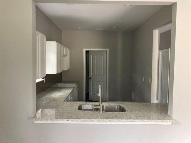 Kitchen featuring a sink, light stone counters, and a peninsula | Image 4