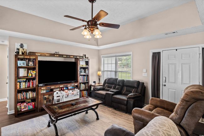 Living area with wood finished floors and a ceiling fan | Image 4