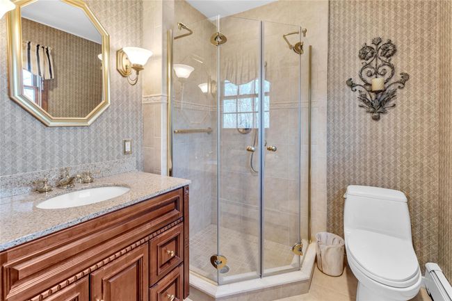 Bathroom featuring vanity, a baseboard heating unit, toilet, wallpapered walls, and a stall shower | Image 15