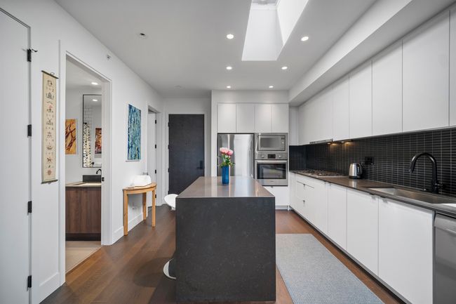 Kitchen featuring appliances with stainless steel finishes, modern cabinets, dark wood-type flooring, a kitchen island, and recessed lighting | Image 4