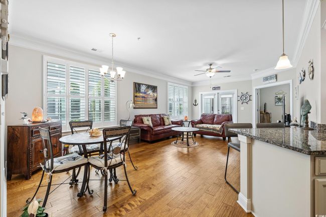 Dining area featuring a ceiling fan, crown molding, light wood finished floors, and a chandelier | Image 14