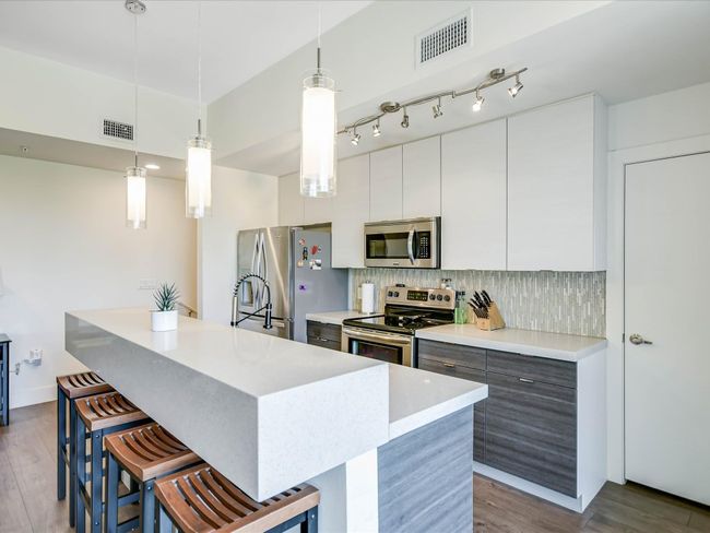 Kitchen featuring stainless steel appliances, a kitchen breakfast bar, modern cabinets, and a center island with sink | Image 11