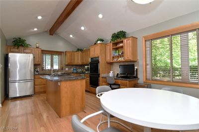 Kitchen featuring plenty of natural light, beamed ceiling, a center island, stainless steel refrigerator, and backsplash | Image 3