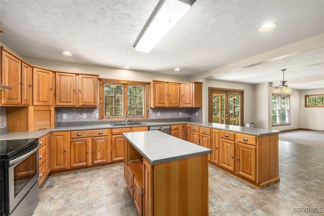 Kitchen featuring backsplash, a kitchen island, sink, hanging light fixtures, and appliances with stainless steel finishes | Image 37