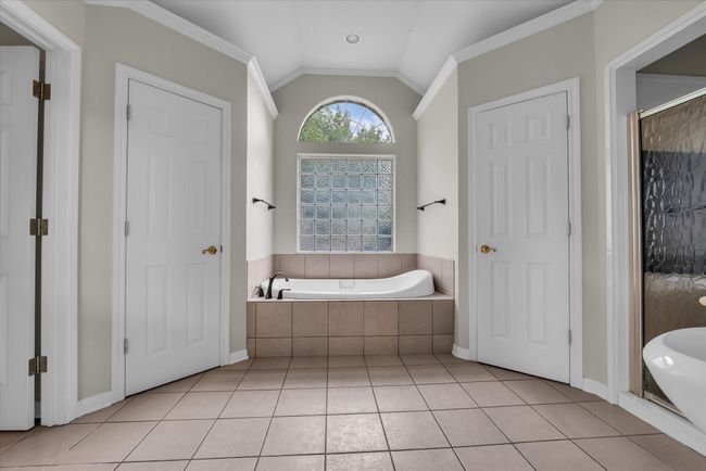 Full bathroom featuring tiled bath, vaulted ceiling, tile patterned flooring, a stall shower, and ornamental molding | Image 20