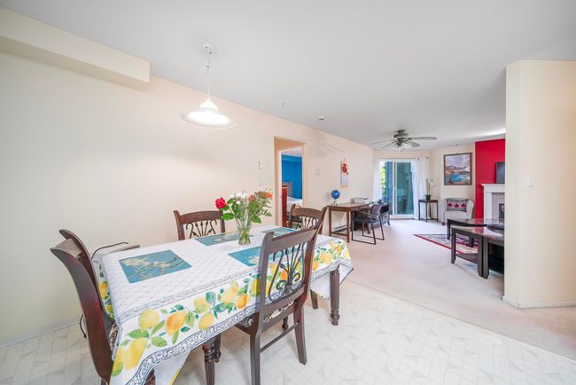 Dining area featuring a ceiling fan, light colored carpet, and a fireplace | Image 23
