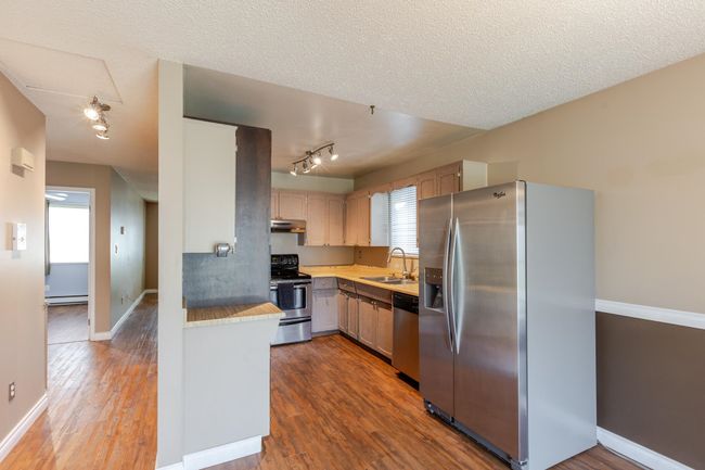 Kitchen featuring dark wood-style flooring, light countertops, baseboard heating, appliances with stainless steel finishes, and a sink | Image 18