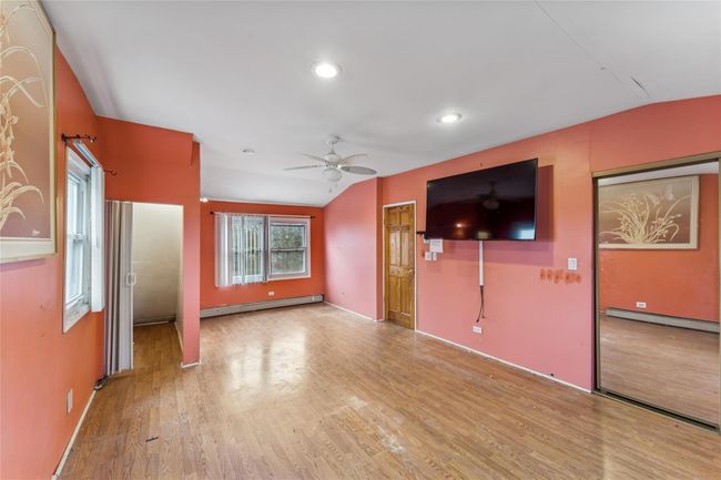 Unfurnished living room featuring baseboard heating, a ceiling fan, wood finished floors, and vaulted ceiling | Image 8