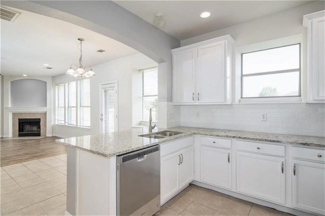 Kitchen with stainless steel dishwasher, light tile patterned flooring, plenty of natural light, white cabinets, and recessed lighting | Image 13
