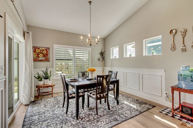 Dining area featuring vaulted ceiling, an inviting chandelier, light wood-style floors, and a wainscoted wall | Image 12